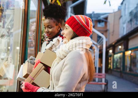 Le donne con i regali che fanno lo shopping della finestra al festival di Natale Foto Stock