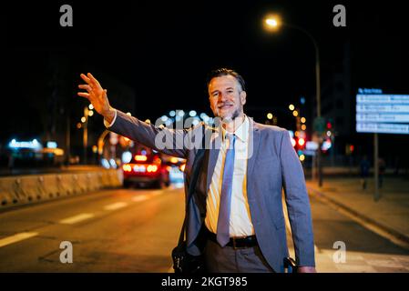 Un uomo d'affari sorridente e maturo che si trova sulla strada Foto Stock