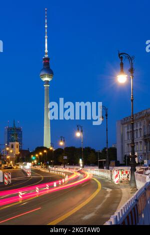 Germania, Berlino, percorsi di luce per veicoli che si estendono lungo la strada illuminata di notte con la Torre della Televisione di Berlino sullo sfondo Foto Stock