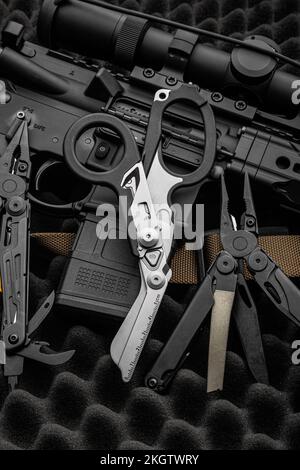 Forbici multifunzione. multitool moderno con molti strumenti. Accanto all'arma si trova uno strumento militare portatile multi-tasking. Sfondo scuro. Foto Stock