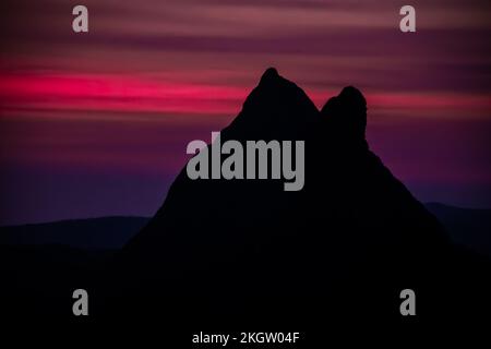 Una silhouette di Monte Beerwah in Glass House montagne sotto il cielo colorato, Australia Foto Stock