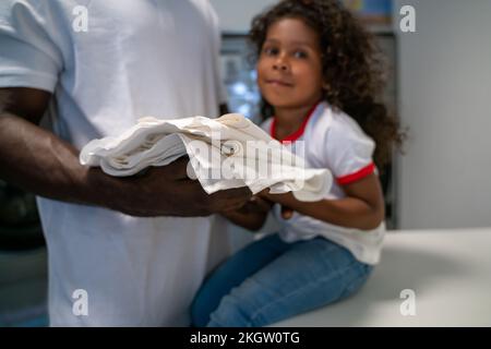 Bambina che aiuta il papà nella lavanderia Foto Stock