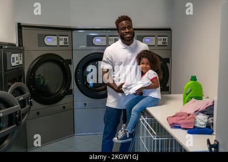 Felice papà e sua figlia carina in una lavanderia Foto Stock