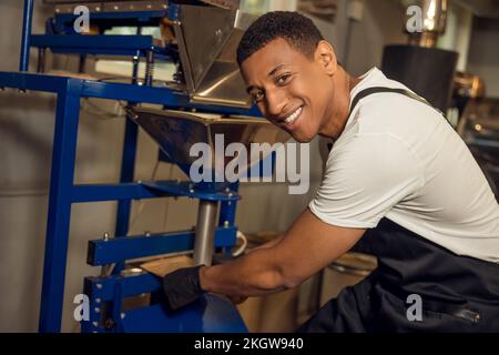 Il dipendente sigilla un sacchetto di carta da caffè con un sigillante a caldo Foto Stock