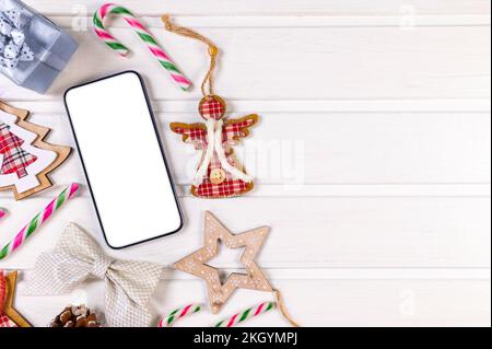 Smartphone mock up con decorazioni rustiche di Natale su tavolo in legno per la presentazione app. Vista dall'alto Foto Stock