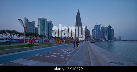 Il tramonto sulla Corniche di Doha mostra il Qatar durante la Coppa del mondo FIFA Qatar 2022 con gente del posto e visitatori che camminano sul lungomare Foto Stock