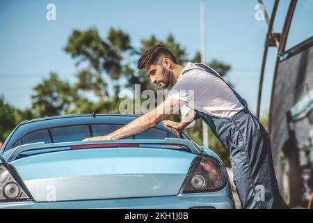 Il dettaglio automobilistico è impegnato a pulire un'automobile del cliente Foto Stock