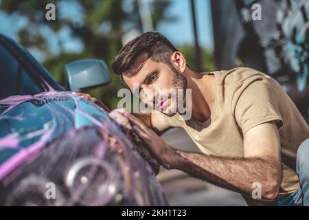 Stazione di servizio concentrata che lava un veicolo del cliente Foto Stock