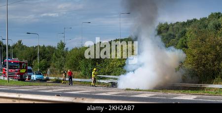 Equipaggio antincendio che mette fuori un incendio di auto dopo un incidente sull'autostrada, Regno Unito. Foto Stock