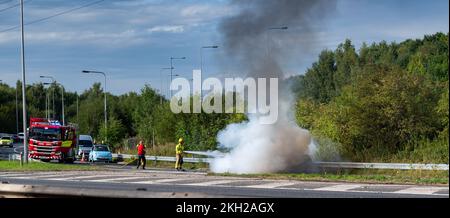 Equipaggio antincendio che mette fuori un incendio di auto dopo un incidente sull'autostrada, Regno Unito. Foto Stock