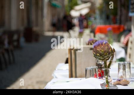 Vaso di vetro con carciofi al tavolo nel ristorante all'aperto Foto Stock
