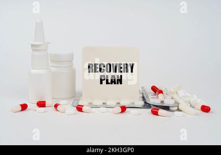 Concetto medico. Su una superficie bianca, blister, compresse, spray e un segno con l'iscrizione - PIANO DI RECUPERO Foto Stock