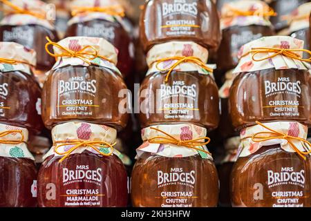 Varietà di Chutney in vasetti di vetro per l'inverno. Salsa di pesche in scatola e chutney di peperoncino e marmellata in vasetti di vetro su ripiano di legno, vista laterale. Nessuno-sur Foto Stock