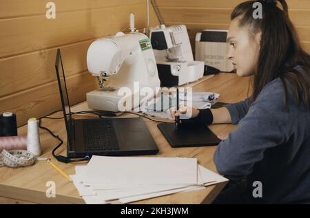 Donna fashion designer disegna un modello di abbigliamento su un tablet grafico. Lavorare su un tablet grafico. Foto Stock