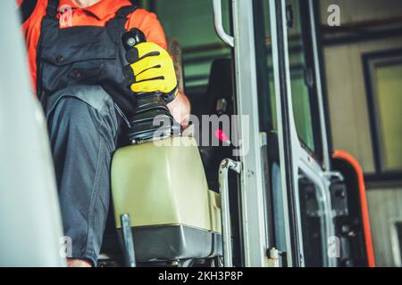 Operatore dell'attrezzatura per impieghi gravosi che tiene la mano sul cambio manuale mentre esce dal garage. Tema macchine industriali. Foto Stock