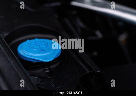 Chiudere il tappo blu del serbatoio del liquido lavavetro nel vano motore. Tappi liquidi all'interno del motore di un'auto. Tappo del serbatoio del liquido lavavetro. Foto Stock