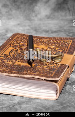 Giornale in pelle, goffrato con il design Celtic Tree of Life, con carta riciclata e penna stilografica. Su uno sfondo di pietra scura Foto Stock
