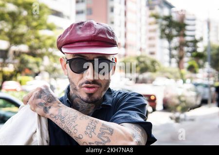 Ritratto di un uomo latino che guarda la telecamera indossando un maglione in un ambiente urbano Foto Stock