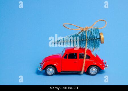 Londra, Inghilterra - Novembre 24 2022: Auto giocattolo rossa e albero di Natale sul tetto su sfondo blu. Macchina giocattolo rossa vintage con un piccolo albero di Natale sul tetto Foto Stock