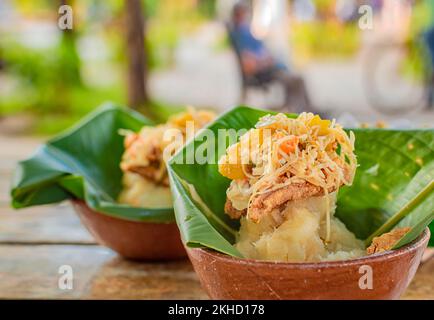 Primo piano di due rinvigoriti serviti su un tavolo di legno. Il rinvigorente cibo tipico di Granada, Nicaragua. Tradizionale Vigoron in foglie di banana servito su un W. Foto Stock