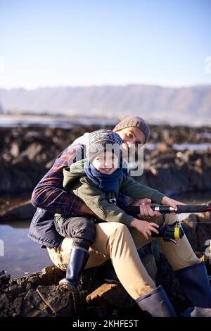 Ho il miglior papà. Ritratto di un padre amorevole e figlio che pesca in riva al mare. Foto Stock