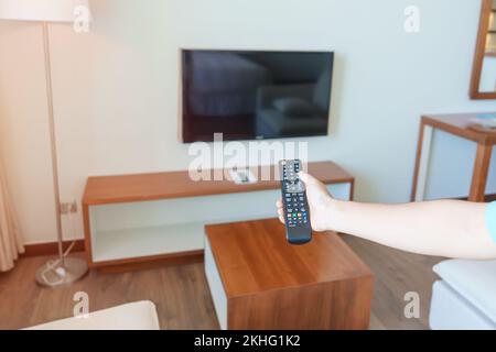 USA il telecomando per regolare lo Smart TV all'interno della stanza moderna di casa. Appartamento concetto di soggiorno Foto Stock