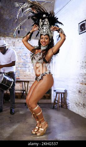 Il ritmo è un ballerino. Una donna etnica attraente che posa nel suo costume di Mardi Gras perline e headdress della piuma. Foto Stock