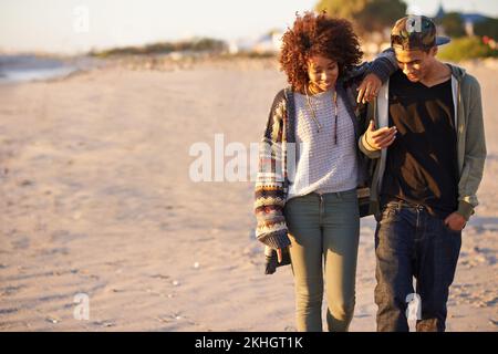 Lunghe passeggiate e colloqui sulla spiaggia. una giovane coppia che si gode una passeggiata sulla spiaggia. Foto Stock