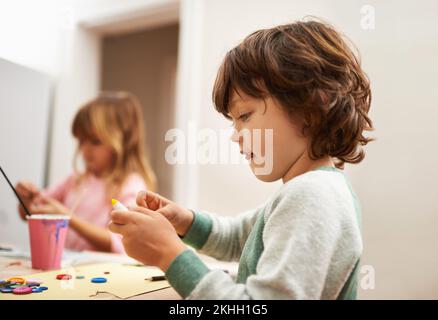 Piccolo compagno astuto. un ragazzino carino che dipinge le uova di pasqua con la sorella. Foto Stock