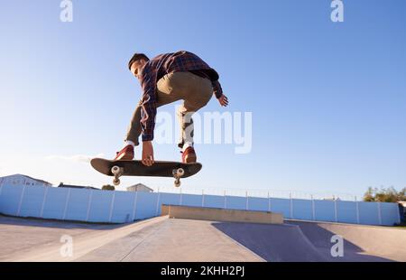 Una giornata al parco di pattinaggio. Un giovane che fa dei trucchi sul suo skateboard al parco skate. Foto Stock