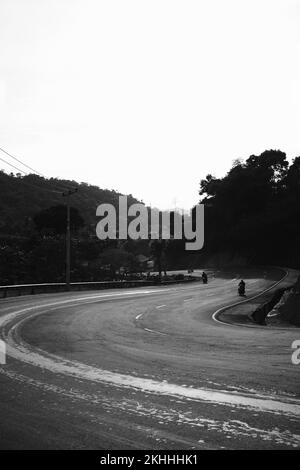 Foto in bianco e nero, foto monocromatica di una strada tortuosa abbandonata che viene raramente passata dai veicoli a Pangandaran - Indonesia Foto Stock