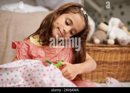 Comò nel fare. una bambina che fa gli abiti da gioco a casa. Foto Stock