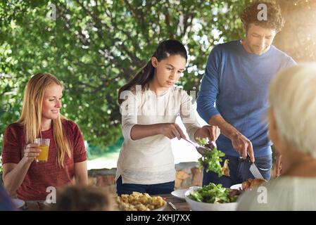 Ama la sua insalata. una famiglia che si prepara a pranzare insieme all'aperto. Foto Stock