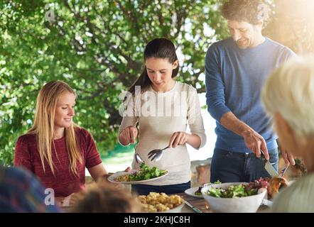 Assicurandosi che ottiene l'abbondanza dei verdi. una famiglia che si prepara a pranzare insieme all'aperto. Foto Stock