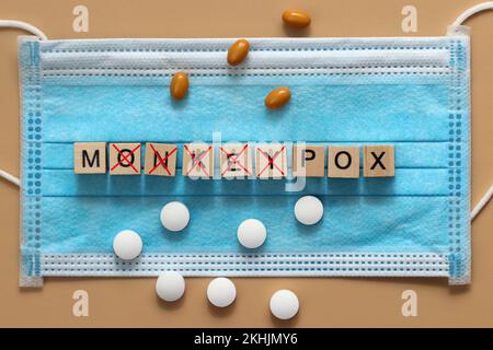 Rinominare il monkeypox della malattia in MPOX. Il virus del vaiolo viene presentato con cubi di legno su una maschera chirurgica. Foto Stock