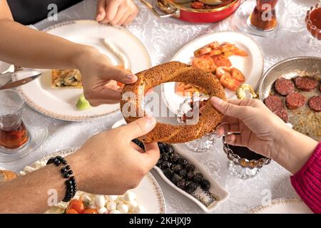 Bagnello turco chiamato simit. Gli amici condividono la colazione tradizionale a casa. Tavolo a sedere che inizia la giornata con un ottimo brunch goloso gourmet. Foto Stock