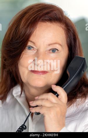 Ritratto di elegante donna adulta di 60s anni seduta al computer in ufficio, donna d'affari . Donna di mezza età matura e fiduciosa in europa Foto Stock