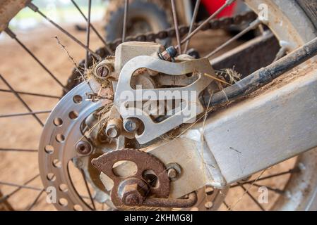 Un primo piano della ruota posteriore di una moto fattoria con erba e sbavature catturate nel freno su una fattoria nel nord-ovest del nuovo Galles del Sud, Australia Foto Stock