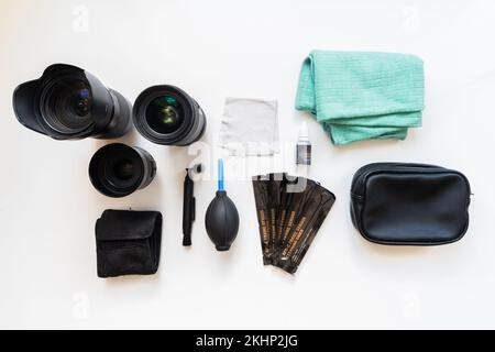 Obiettivi per fotocamere DSLR, filtri, tamponi, detergente per sensori, soffiatore d'aria, Penna in microfibra e lente inserita su sfondo giallo testurizzato. Set per la pulizia di foto Foto Stock