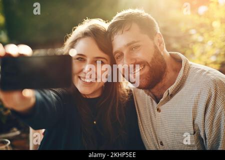 Felice, telefono e coppia amano prendere un selfie in un ristorante all'aperto per un appuntamento romantico in primavera. Relax, memoria e la giovane donna che scatta foto Foto Stock