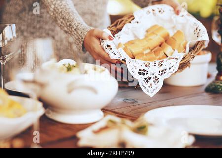 Donna, paniere e cibo al tavolo da pranzo in casa, casa e sala da pranzo per il pranzo di famiglia, pasto e ospitare incontri sociali insieme. Primo piano Foto Stock