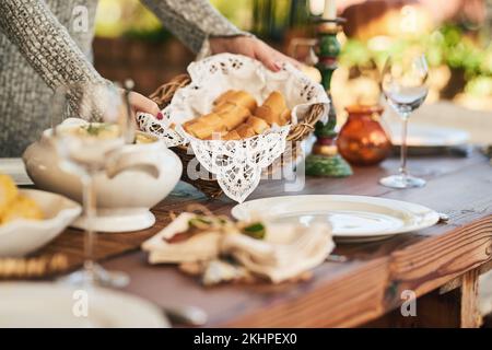 Cibo, pane e festa con le mani di donna al tavolo da pranzo per l'ospitalità, vacanza o celebrazione. Cucina, decorazione e pranzo con servizio di ragazza Foto Stock