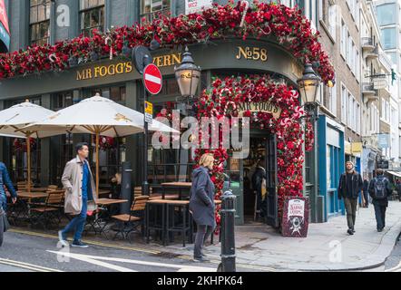 Coloratissime ghirlande natalizie decorano la facciata della Taverna MR Fogg's all'angolo tra New Row e St Martin's Lane, Covent Garden, Londra, Inghilterra, Regno Unito Foto Stock