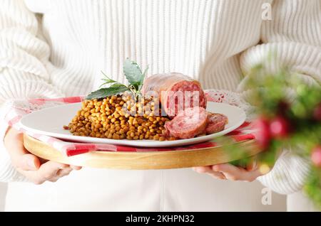 Festive Cristmas Cotechino italiano con lenticchie su piatto bianco. Foto Stock