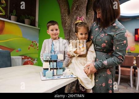 Ternopil, Ucraina - 17 novembre 2022: Madre con tre bambini e torta congelata in festa di compleanno bambino. Foto Stock