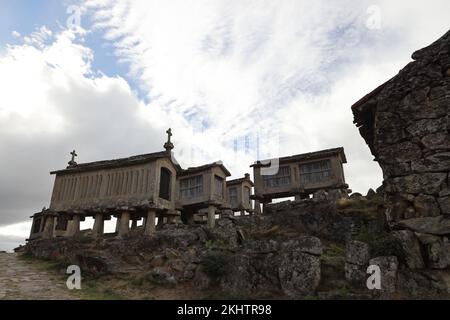 Un vecchio granaio (espigueiros) e castello sopra il villaggio di Lindoso nel Parque Nacional da Peneda-Geres nel nord del Portogallo. Foto Stock