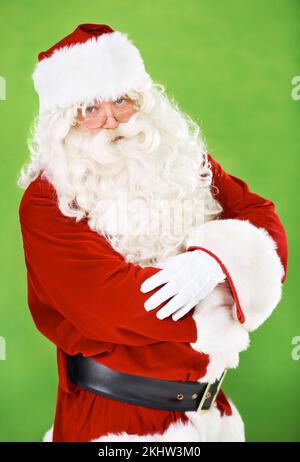 Natale, babbo natale e costume con un uomo in studio su uno sfondo verde per la celebrazione di stagione festiva. Ritratto, occhiali e atteggiamento serio di Foto Stock