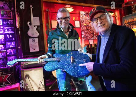 24 novembre 2022, Amburgo: Il chitarrista Jens Ritter (l) e otto Waalkes esibiscono la chitarra del '25th° anniversario di Magic & Freedom', costellata di oltre 11.000 pietre Swarovski, presso lo Zwick St. Pauli. Il chitarrista Jens Ritter presenta alcuni dei suoi strumenti al pub di culto 'Zwick' di Amburgo-St Pauli. Le chitarre elettriche e i bassi elettrici di Ritter sono acquistati non solo da musicisti ma anche da collezionisti e musei; i suoi strumenti sono esposti anche al Metropolitan Museum of Art (New York) allo Smithsonian American Art Museum (Washington, DC) e al Technoseum (Mannheim). P Foto Stock