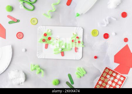 Il bambino fa un collage di carta di Natale di biglietto d'auguri. Realizzato con le proprie mani. Progetto artistico per bambini. Artigianato per bambini. Vista dall'alto Foto Stock