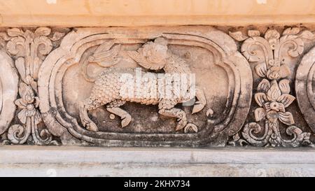 Antico stucco a bassorilievo di animali mitologici con zoccoli e scale su parete della biblioteca di hor trai, tempio di Wat Phra Singh, Chiang mai, Thailandia Foto Stock